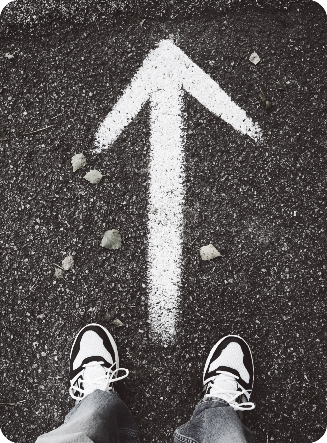 Feet facing a forward-pointing arrow on pavement, symbolizing clarity, direction, and taking the right steps in product and technology decisions.